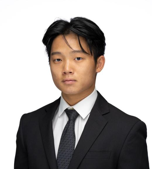 Young man in a suit and tie, posing against a plain white background.